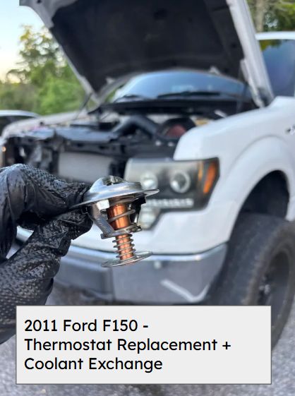 Mechanic holding the old thermostat in front of the open hood of a 2011 Ford F-150