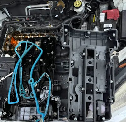 Engine of a 2015 Chevy Trax with the valve cover removed and the new gasket laid out
