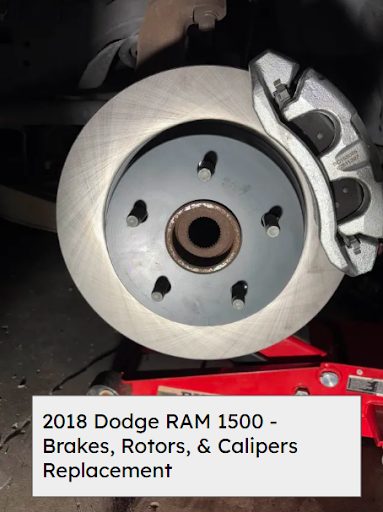 New front brake rotor and caliper installed on a 2018 RAM 1500 raised on a floor jack