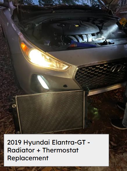 Old radiator removed in front of a 2019 Hyundai Elantra GT with the hood open